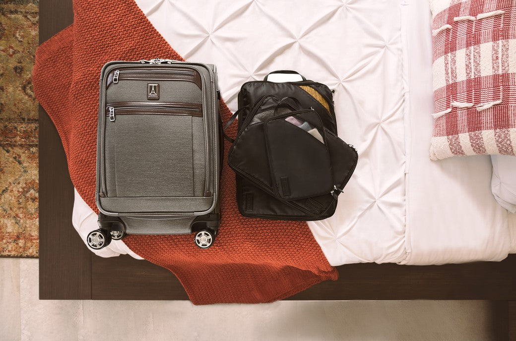 suitcase on bed with packing cubes next to it