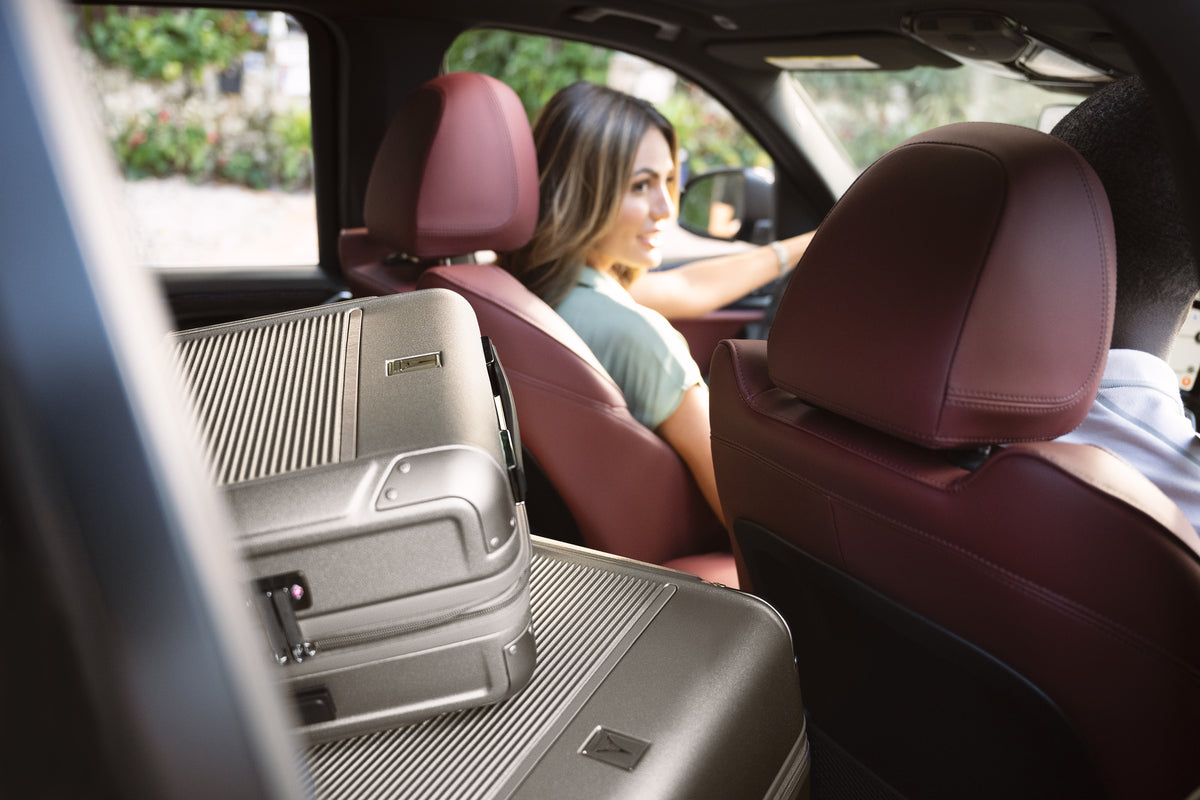 
Man and women in a car with hardside suitcases in the back seat