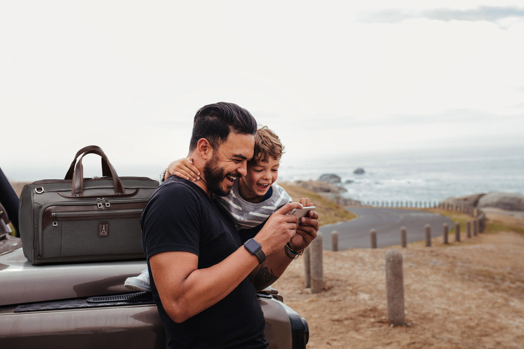 Father and son sitting on end of truck on the beach with a Platinum Elite Duffel Bag next to them