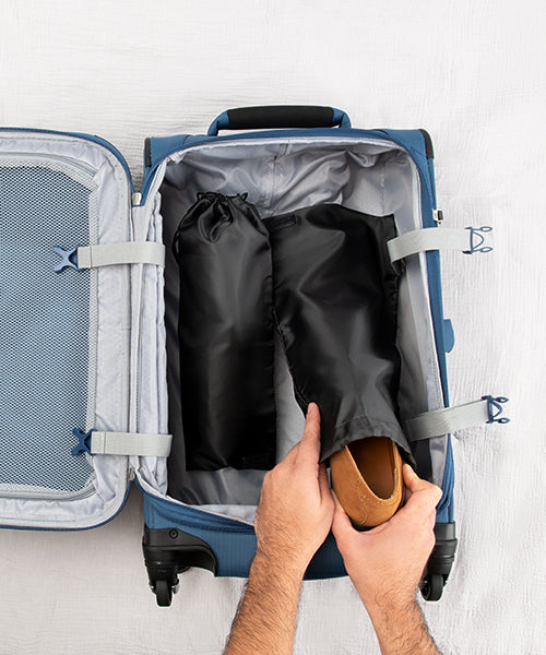 someone putting shoes in a shoe bag inside a suitcase